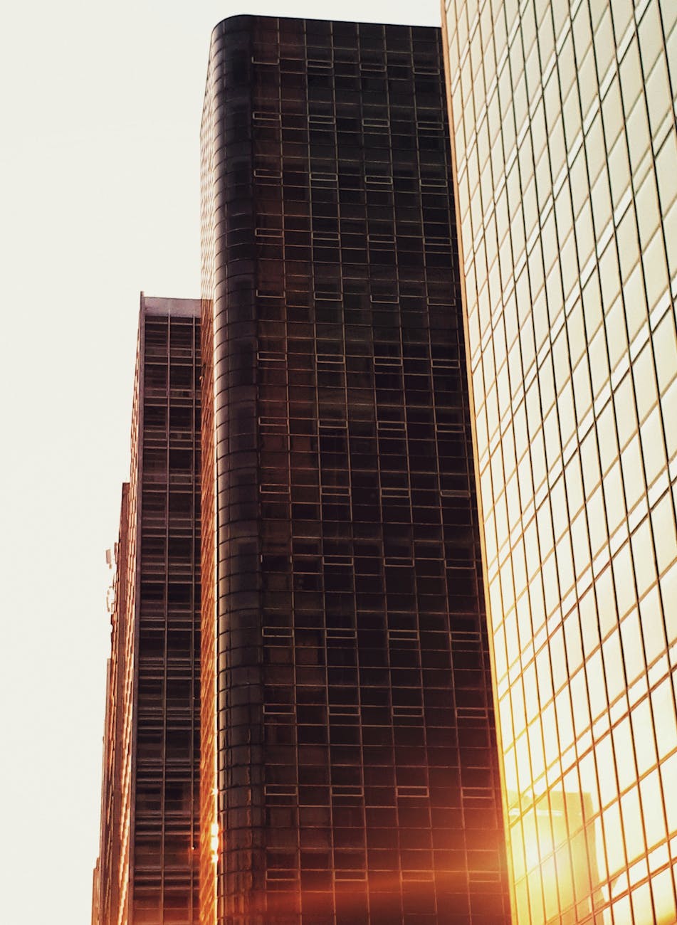 Miami downtown skyline at golden hour, glass office towers reflecting warm sunset light, deep teal and lime green color grade, cinematic wide-angle editorial architectural photography