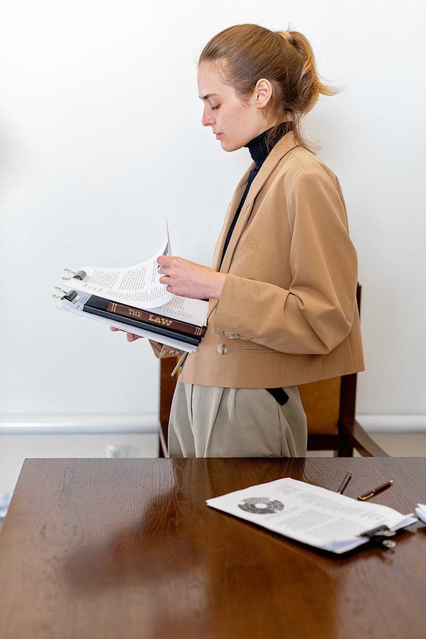 Legal assistant organizing case files in law firm library with bookshelves