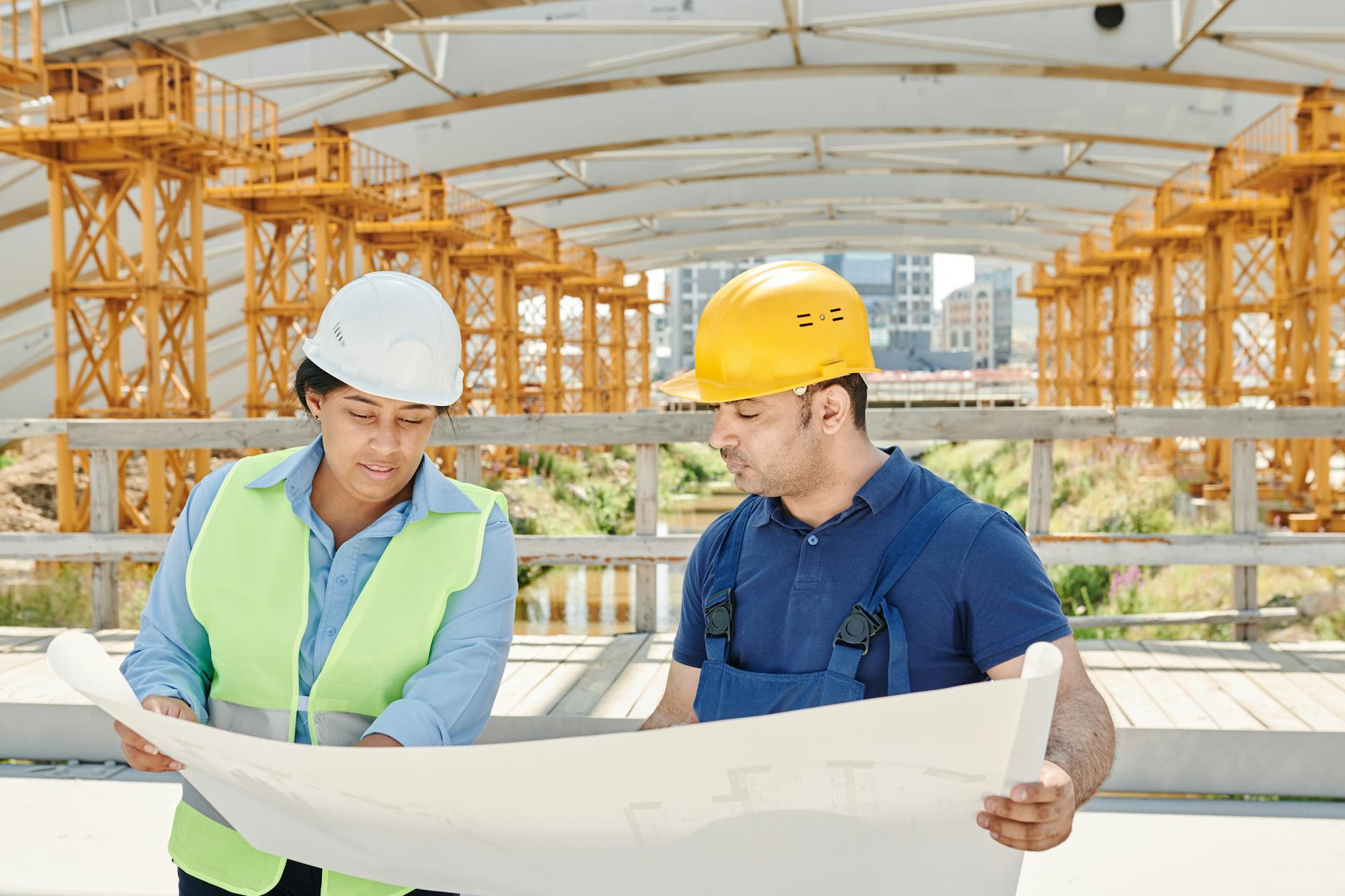 Construction project coordinator reviewing blueprints on jobsite with hard hat